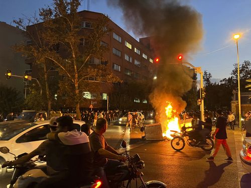 A police motorcycle and a trash bin are burning during a protest over the death of Mahsa Amini, a 22-year-old woman who had been detained by the nation's morality police, in downtown Tehran, Iran. This photo was taken by an individual not employed by the Associated Press on September 19, 2022 and obtained by the AP outside Iran.