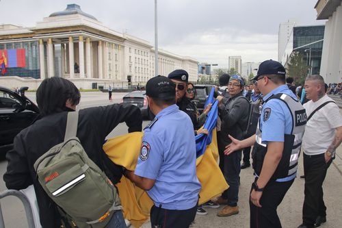Police and security officers prevent members of the "No War" group from holding up a Ukrainian flag during the visit of Russian President Vladimir Putin in Ulaanbaatar, Mongolia