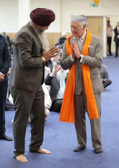 King Charles III makes the namaste gesture as a traditional shawl for meditation is placed around his shoulders in the Prayer Hall during a visit to the newly built Guru Nanak Gurdwara on December 06, 2022 in Luton, England 