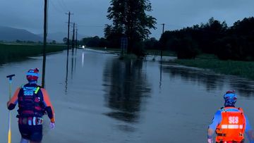 SES workers walk through flooded areas near Murwillumbah in the Northern Rivers