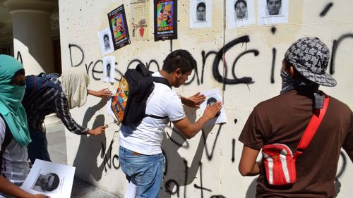 Protesting students paste images of the 43 missing students on the walls of the main Guerrero state courthouse in the city of Chilpancingo, Mexico in 2016. 