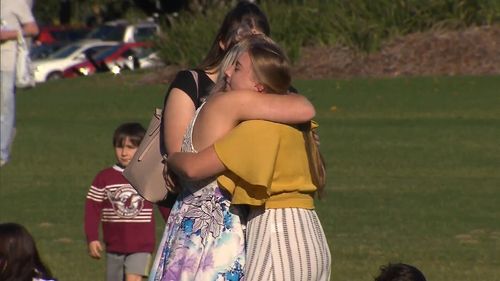 A pair of girls embrace at the memorial, held at Strathpine Park. (9NEWS)