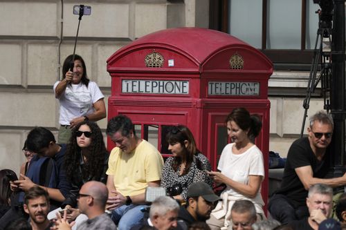 People wait near Parliament Square before the procession of the gun carriage which will carry Queen Elizabeth II's coffin from Buckingham Palace to Westminster Hall in London, Wednesday, September 14, 2022. The Queen will lie in state in Westminster Hall for four full days before her funeral on Monday, September 19 (AP Photo/Frank Augstein, Pool)