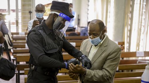 A policeman handcuffs Paul Rusesabagina, right, whose story inspired the film "Hotel Rwanda", before leading him out of the Kicukiro Primary Court in the capital Kigali, Rwanda Monday, Sept. 14, 2020