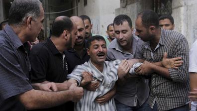 Des proches aident Hazem Eshbair, qui a perdu deux de ses enfants, tués avec 8 autres personnes, toutes sauf une, des enfants, dans une explosion dans un parc du camp de réfugiés de Shati, dans le nord de la bande de Gaza, le lundi 28 juillet 2014. Les autorités israéliennes et palestiniennes se sont mutuellement blâmées pour l'attaque et les combats dans la guerre de Gaza ont fait rage malgré une grande fête musulmane.  (Toutes les photos : Getty/AP/AFP) 
