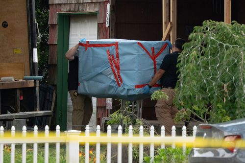 New York State police officers carry out an large item from the home of Rex Heuermann