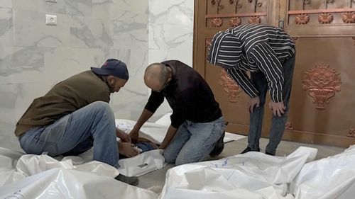 Family members unzips a body bag of children killed by by Israeli airstrikes in the morgue in the city of Khan Younis, southern Gaza Strip, Friday, Oct. 25, 2024. (AP Photo)