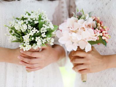 Two women holding wedding bouquets, close up on their hands.