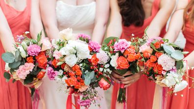 Bridesmaids and bride holds bouquets of flowers in hand.