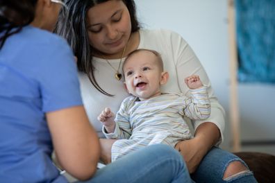 Baby smiles while being examined by a nurse or doctor during a house call medical exam