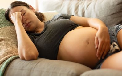 Pregnant woman uncomfortable, lying on couch. morning sickness