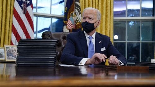 President Joe Biden pauses as he signs his first executive orders in the Oval Office of the White House on Wednesday, Jan. 20, 2021, in Washington. (AP Photo/Evan Vucci)