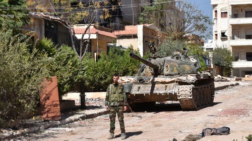 A Syrian pro-government soldier stants next to a tank at the '1070' apartment block area, south of al-Hamdaniyah, in eastern Aleppo.  (AFP)