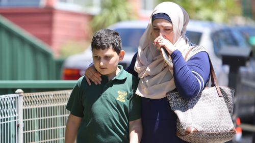 A distressed parent leaves the school with their child. (AAP)