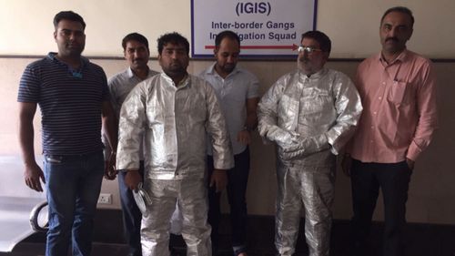 Dressed in "space suits", the two men were arrested by police for conning a businessman.