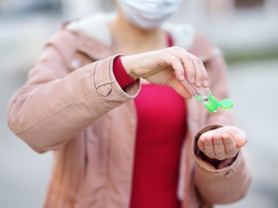 Woman sanitising her hands while wearing a face mask