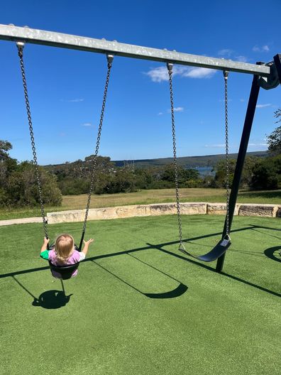 Amy pushing her daughter on a swing at the park