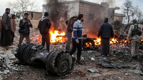 People walk amidst the rubble of the Russian Sukhoi Su-25 fighter jet. (AAP)