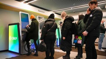 People stand in line to withdraw money from an ATM in Sberbank in St. Petersburg, Russia.