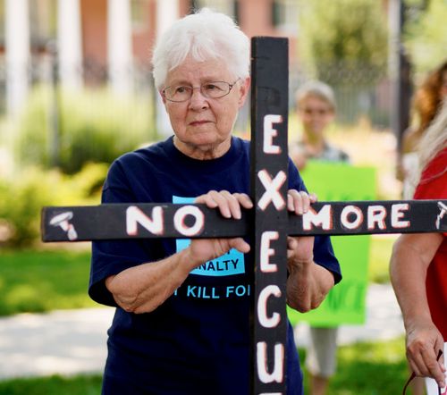 Campaigner Marylyn Felion holds on to a cross reading "No More Executions" as she pickets with others against the death penalty, in front of the governor's mansion in Lincoln, Nebraska.