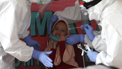 Health worker takes a nasal swab sample from a girl during a public testing for the new coronavirus conducted in Jakarta, Indonesia Monday, June 15, 2020.(AP Photo/Achmad Ibrahim)