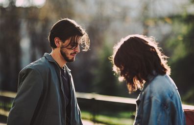 Boyfriend and girlfriend looking down while standing together on street