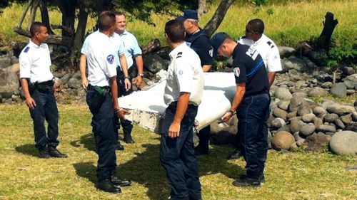 Police and gendarmes carry a piece of debris from an unidentified aircraft found in the coastal area of Saint-Andre de la Reunion. (AFP)