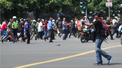 One of the gunman walks on the street as crowds flee. (Veri Sanovri/Xinhua via AP)