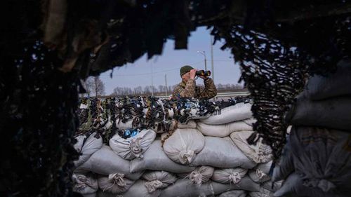 A Ukrainian soldier looks through binoculars at a military check point, in Lityn, Ukraine.