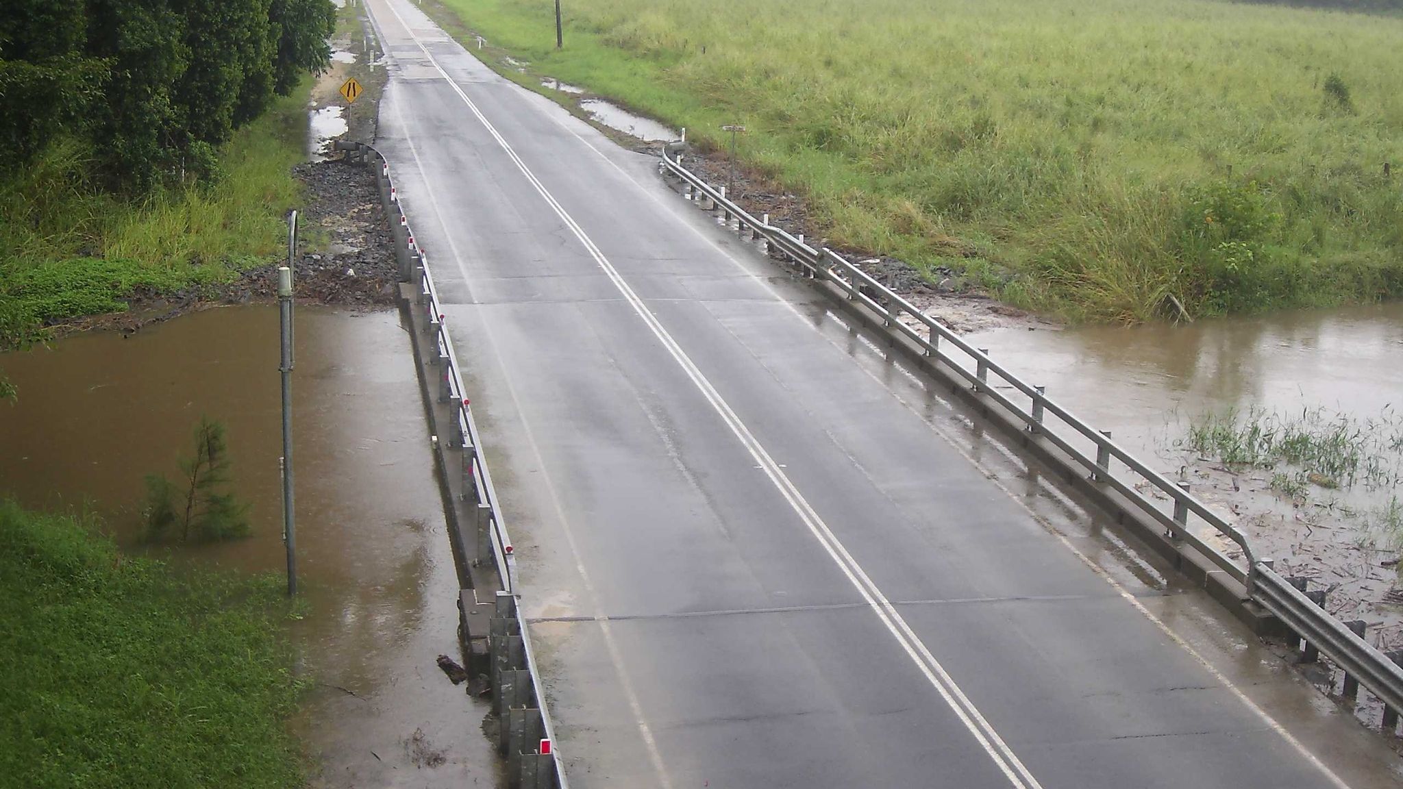The muddy brown water of Bushy Creek swirled below the bridge on Mount Molloy Road.