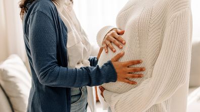 Woman touching pregnant mum's belly.