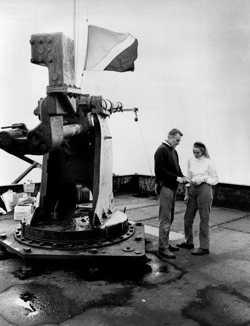 Standing next to an old anti-aircraft gun which was left over from World War II, Roy Bates explains to his wife Joan how to use a handgun