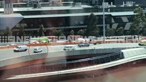 Seemingly oblivious to other motorists, the white car stops on the bridge before driving against traffic.