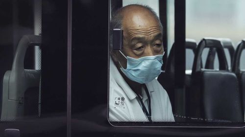 A man wearing a face mask to protect against coronavirus rides alone on a bus in Beijing.