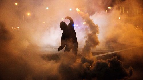 A protester hurls a smoke bomb canister back towards police. (AAP)