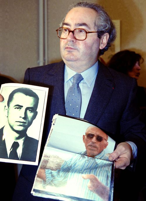 Nazi hunter Serge Klarsfeld displays two photos of WWII criminal Alois Brunner at a press conference in Paris on January 11, 1989. (Getty Images)