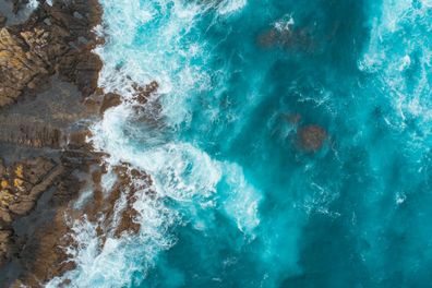 Stock image of ocean current, waves crashing against rocks.