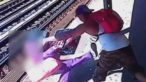 The CCTV shows a man throwing a woman onto the tracks.