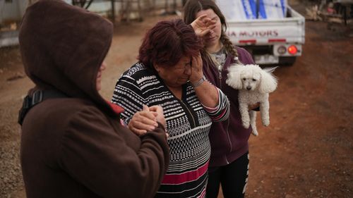 Rosa Munoz, centre, reacts after fires destroyed her house in Tome, Chile, Saturday, Feb. 4, 2023. 