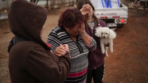 Rosa Munoz, au centre, réagit après que des incendies aient détruit sa maison à Tome, au Chili, le samedi 4 février 2023. 