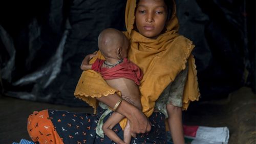A pregnant Rohingya Muslim, Noor Aysha, clutches her 10-month-old son Anamul Hassan inside her shelter in the Thaingkhali refugee camp in Bangladesh.