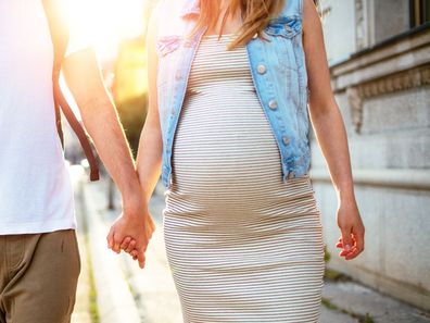 Man walking hand in hand with pregnant partner