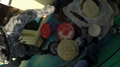 Food can be seen laid out on the floor in preparation for an evening meal. (Royal Australian Navy)