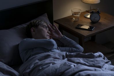 Depressed senior woman lying in bed cannot sleep from insomnia