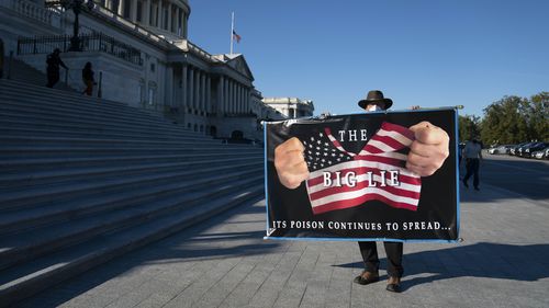 Un protestatar deține un semn în fața casei Capitolului Statelor Unite din Washington, DC. 