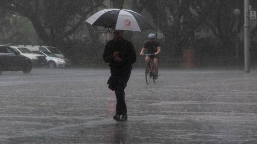 Pedestrians walk through the heavy rainfall in Sydney's CBD.