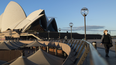 A woman in a mask walks through the Sydney Opera House forecourt on August 17, 2020 in Sydney, Australia. (Photo by Brook Mitchell/Getty Images)