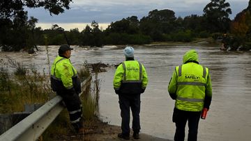 People looks at the Menangle bridge that crosses the Nepean River which is under water and where two cars were inundated by the rising flood waters . Menangle, NSW. June 7, 2024.  