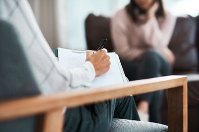 Cropped shot of a psychologist writing notes during a therapeutic session with her patient