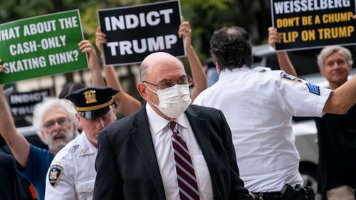 Allen Weisselberg enters court surrounded by protesters.